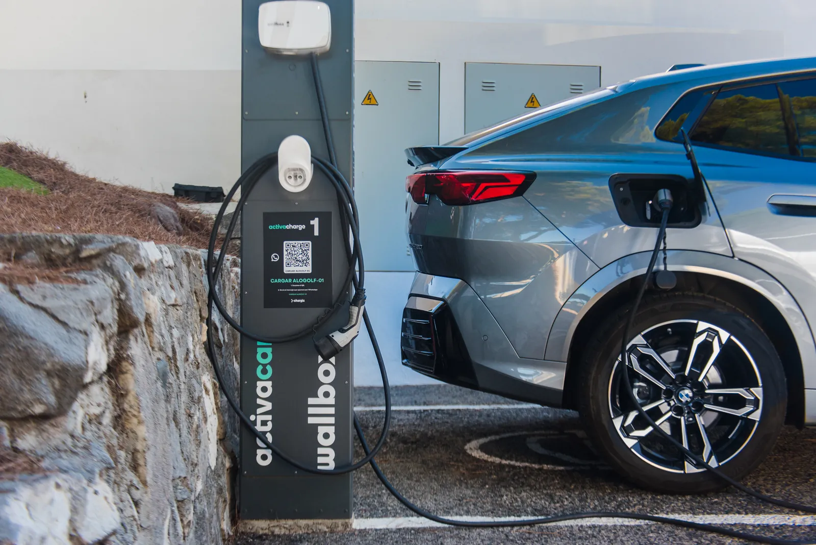 Coche eléctrico cargando en un punto de recarga con código QR